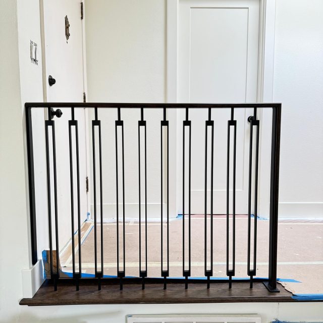 Custom black iron railings with slim vertical bars, installed on a contemporary staircase.