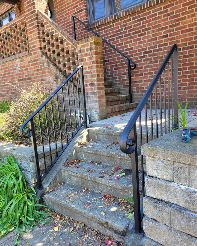 Black exterior stair railings with a lamb’s tongue handrail end and vertical bars.