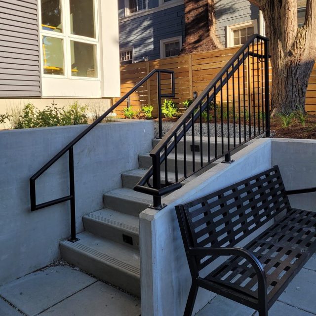 Black vertical railings with a matching handrail installed on an outdoor stairway.