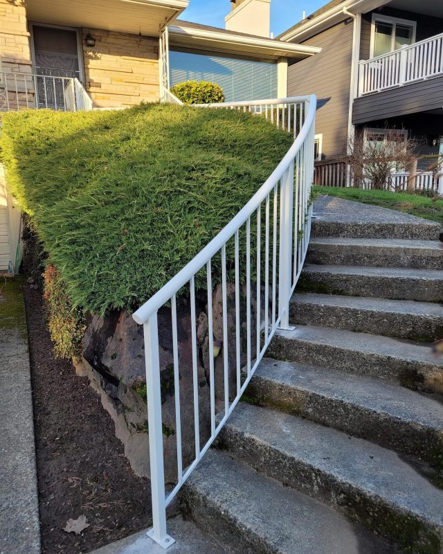 White vertical metal stair railings installed along a concrete outdoor staircase.