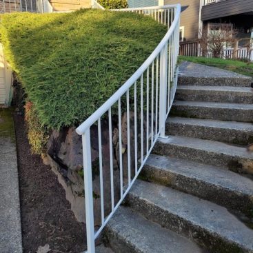 White vertical metal stair railings installed along a concrete outdoor staircase.
