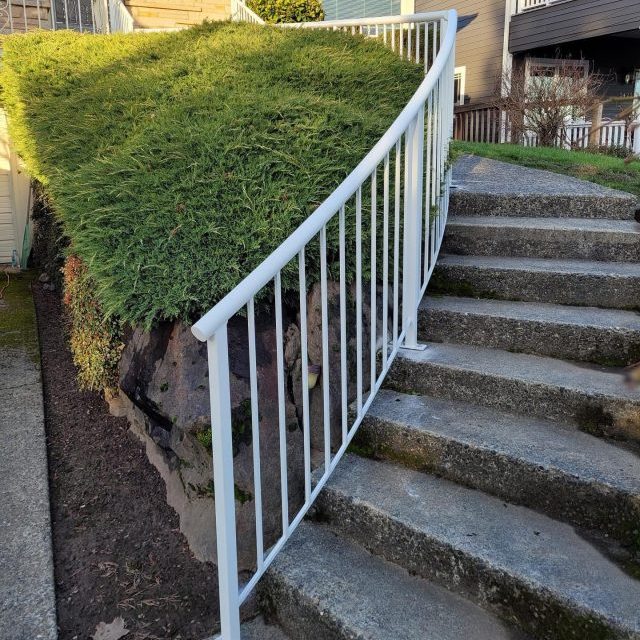 White vertical metal stair railings installed along a concrete outdoor staircase.