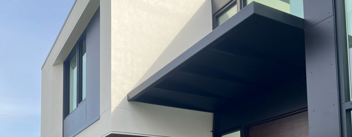 Custom fabricated black metal awning installed above a glass entryway of a modern home in Bellevue, Washington by Custom Railings WA