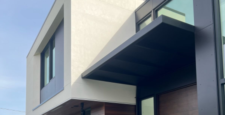 Custom fabricated black metal awning installed above a glass entryway of a modern home in Bellevue, Washington by Custom Railings WA