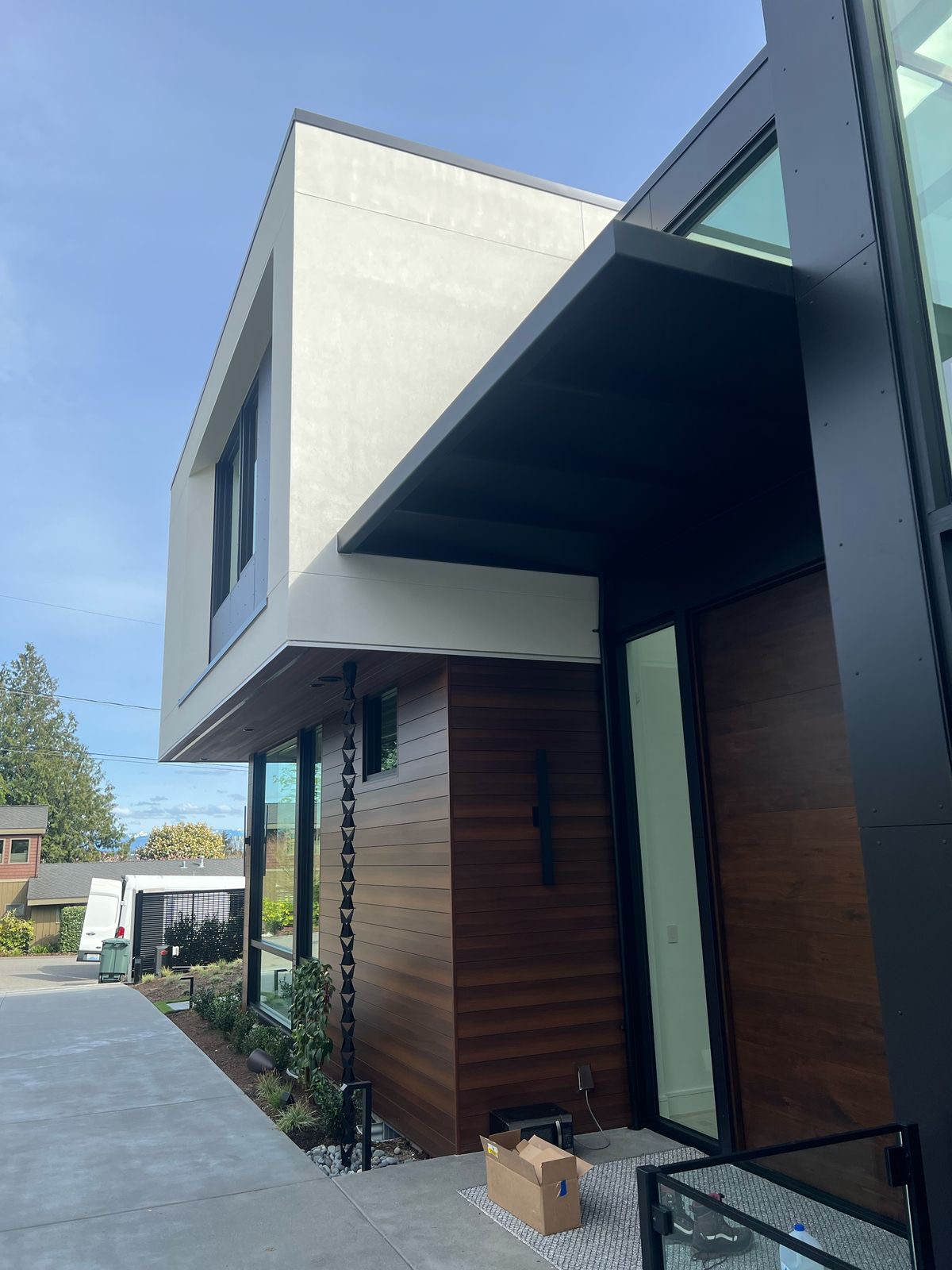 Custom fabricated black metal awning installed above a glass entryway of a modern home in Bellevue, Washington by Custom Railings WA