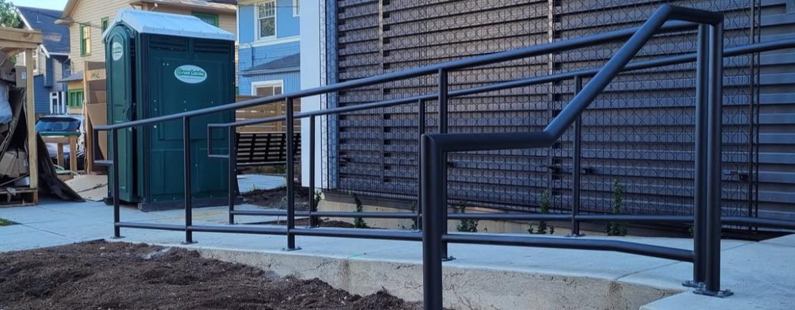 Custom powder-coated commercial steel railings installed on an ADA-compliant ramp at a Seattle commercial building.