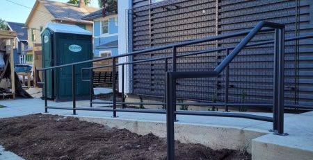 Custom powder-coated commercial steel railings installed on an ADA-compliant ramp at a Seattle commercial building.