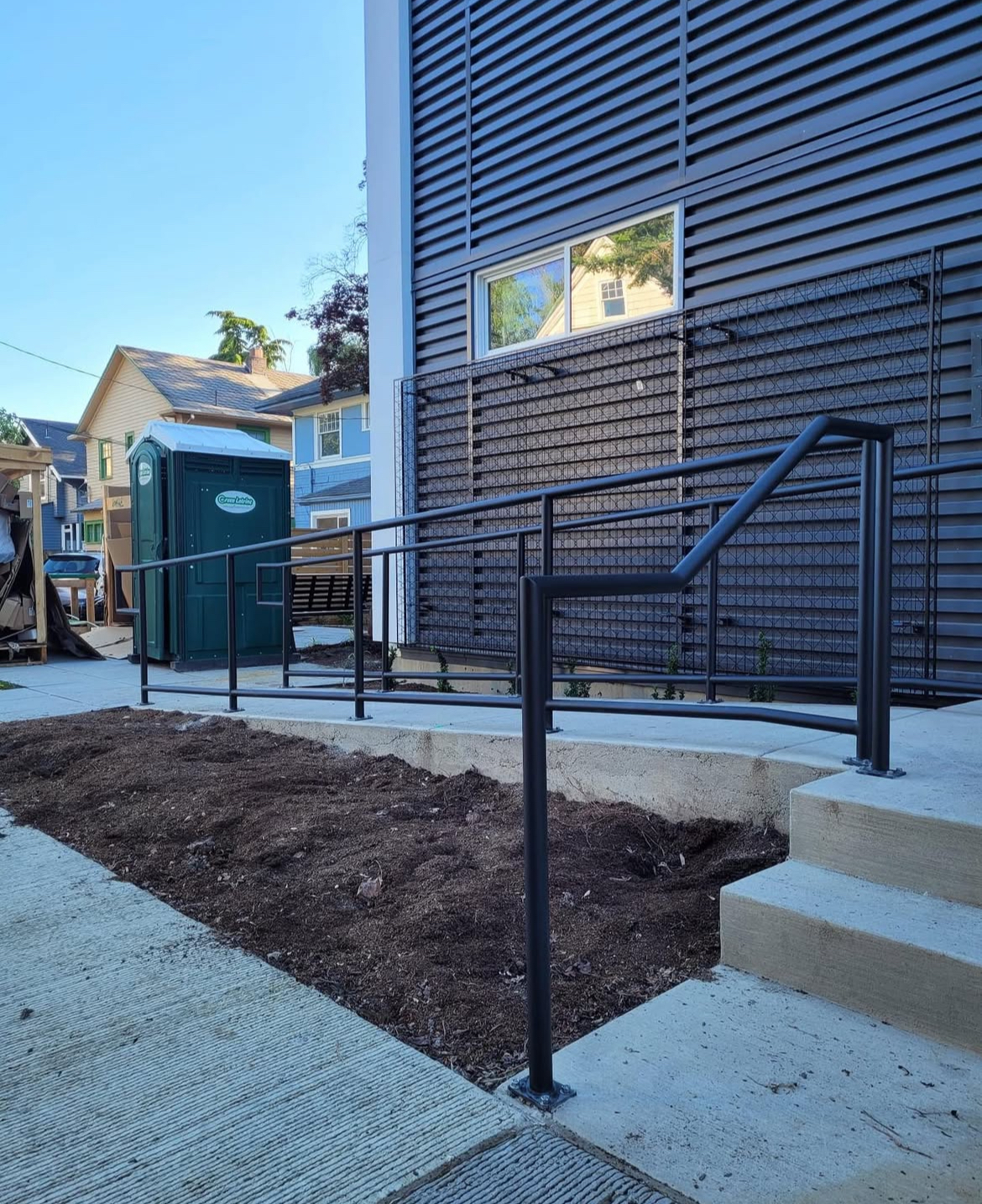 Custom powder-coated commercial steel railings installed on an ADA-compliant ramp at a Seattle commercial building.