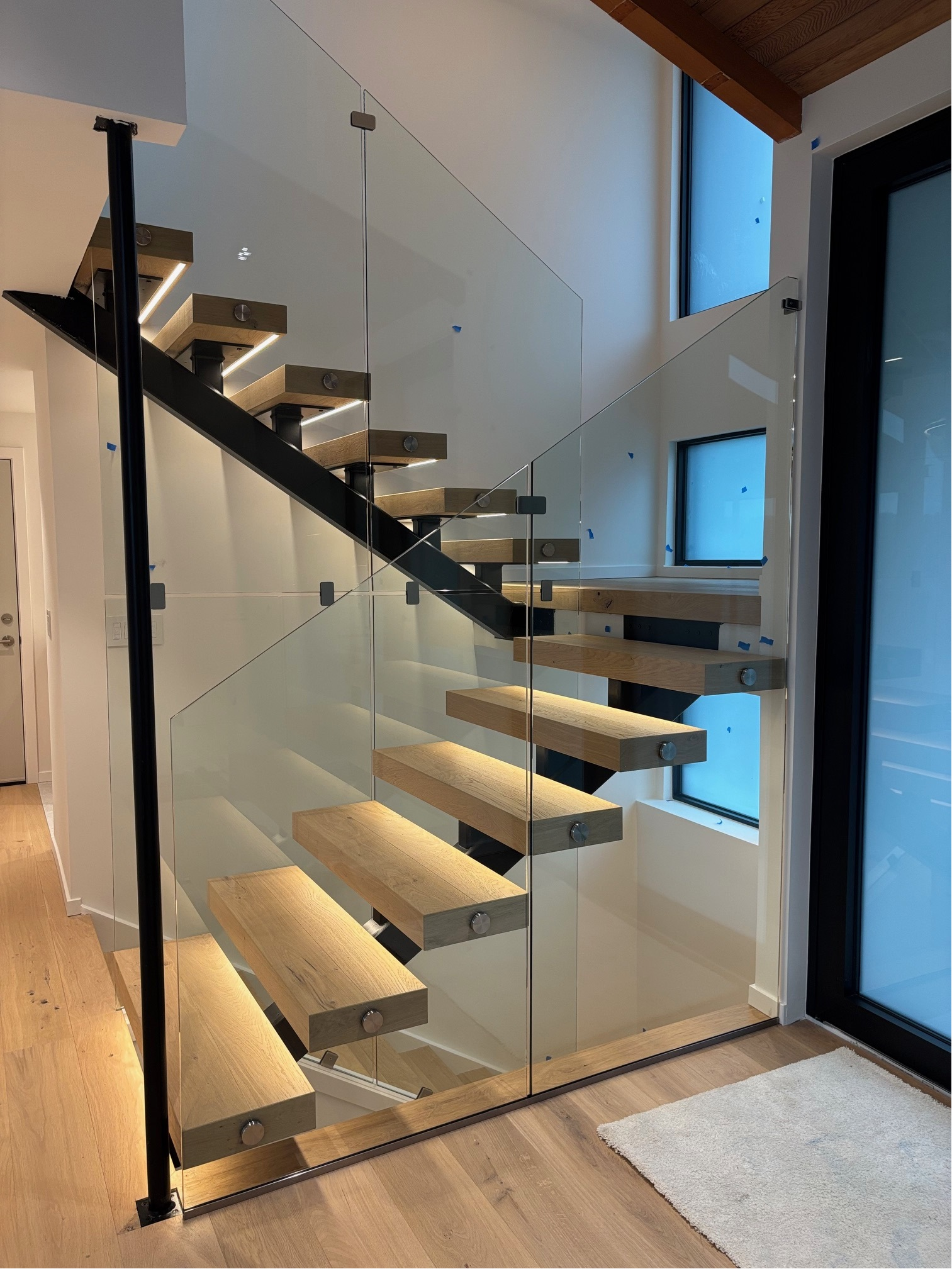 Floating stairs with full-height frameless glass railings in a modern Seattle home
