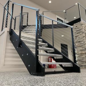 Interior stair railing with black posts, stainless cable infill, and wood treads in Enumclaw WA