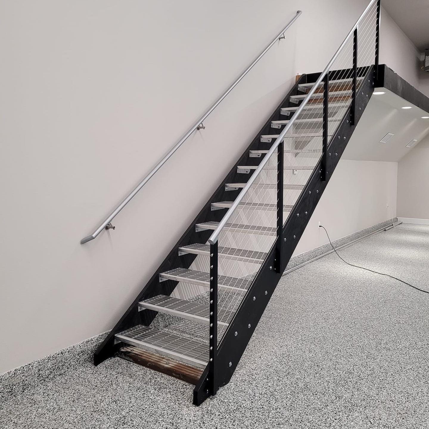 Metal stair railing with cable infill and grated treads in a commercial interior
