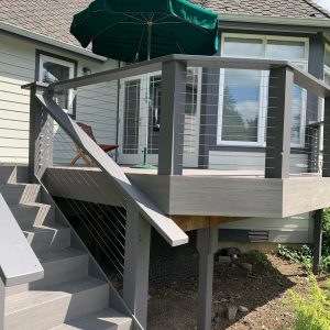 Exterior cable deck railing with gray posts and top rail on a backyard deck in Redmond, WA