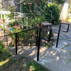 Modern black steel handrail with rectangular geometric accent on outdoor steps in Seattle, WA