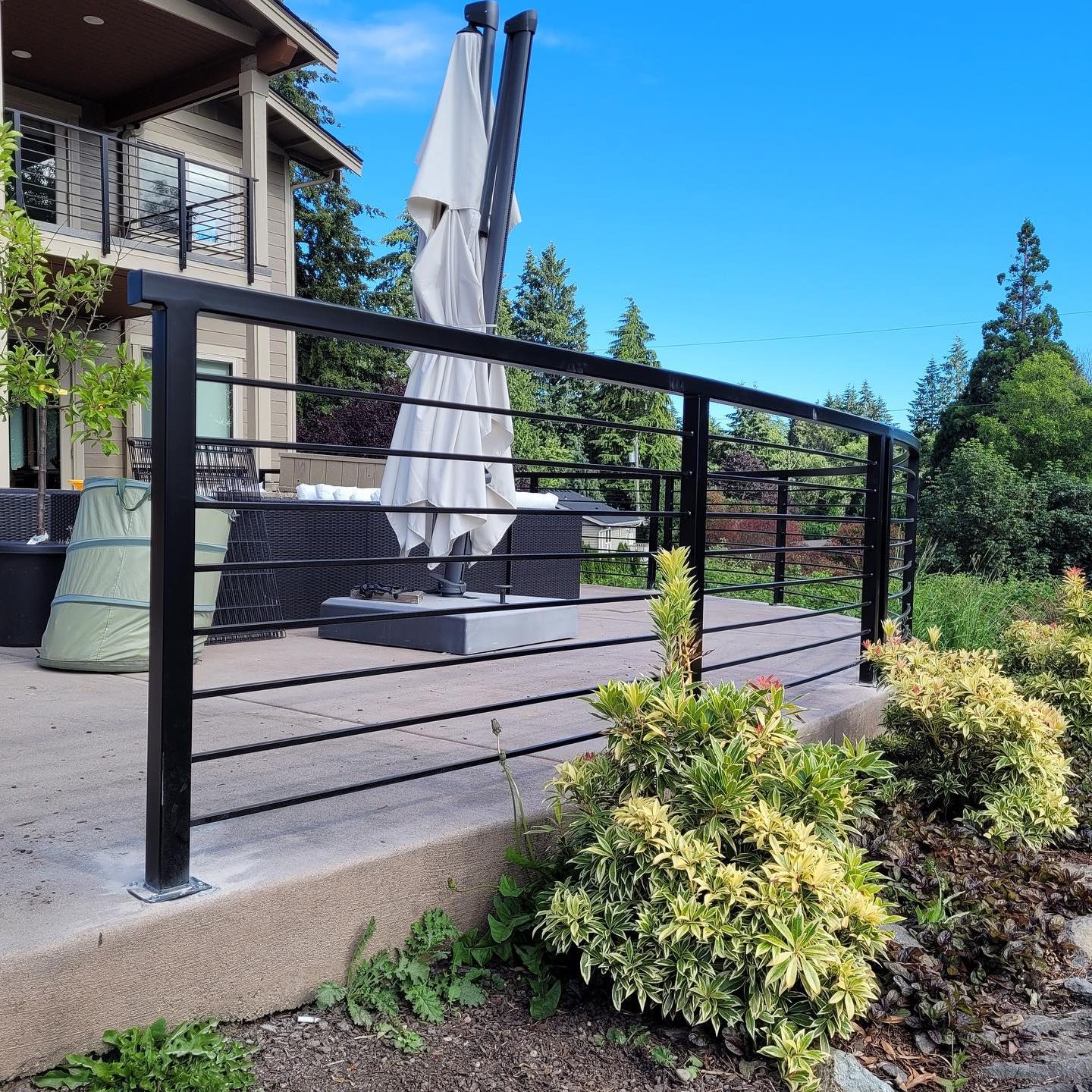 Curved black horizontal bar railing installed on a patio edge in Renton, WA