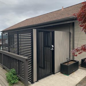 Modern privacy fence and gate with black metal frame and composite/wood-look panels in Seattle, WA