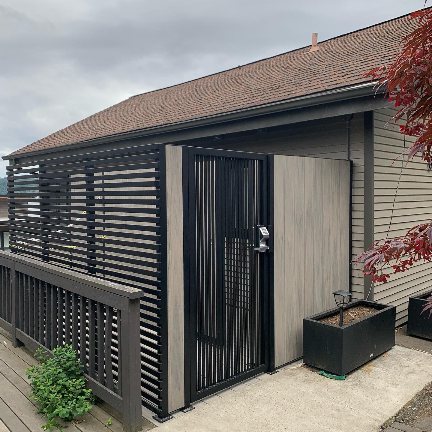Modern privacy fence and gate with black metal frame and composite/wood-look panels in Seattle, WA