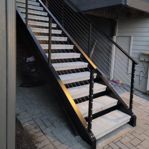 Exterior stair system with black posts and stainless cable railing on a modern home in Seattle, WA