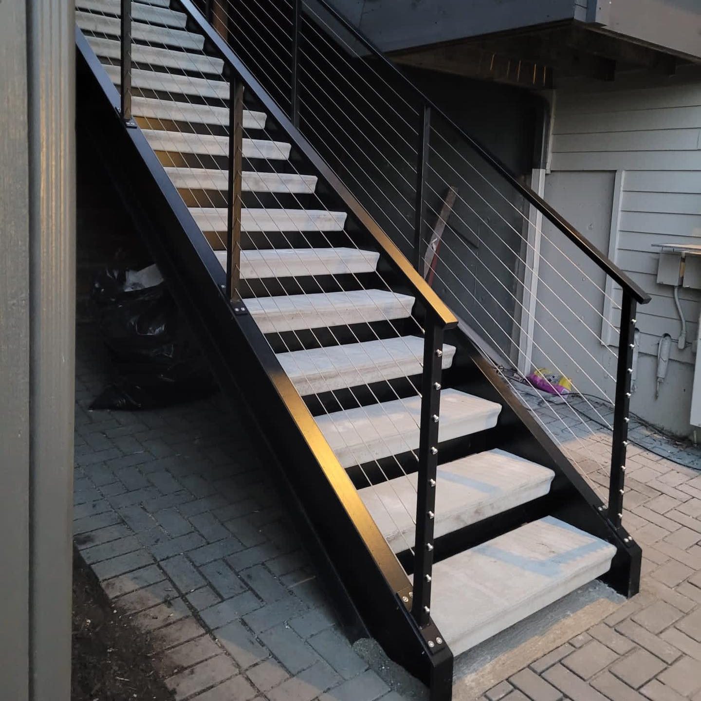 Exterior stair system with black posts and stainless cable railing on a modern home in Seattle, WA