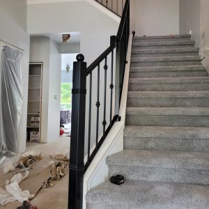Traditional black interior stair railings with decorative iron balusters and a bold newel post in Olympia
