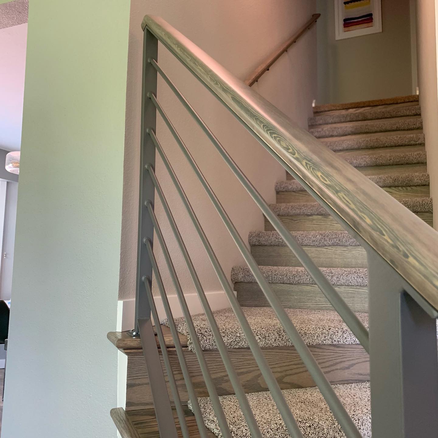 Gray interior stair railing with horizontal bars and a wood handrail in Renton, WA