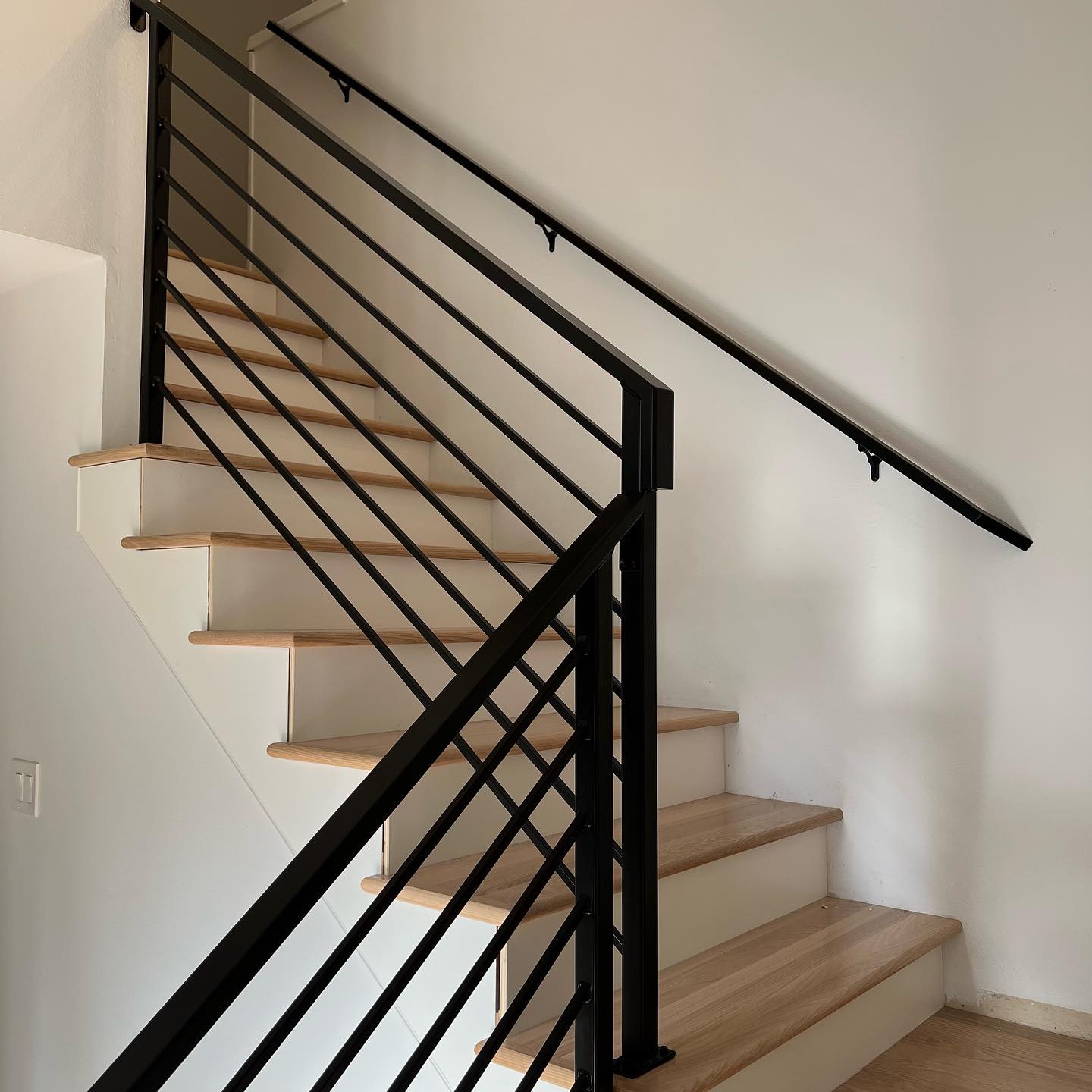 Interior landing guardrail with black steel posts and horizontal rails overlooking stairwell