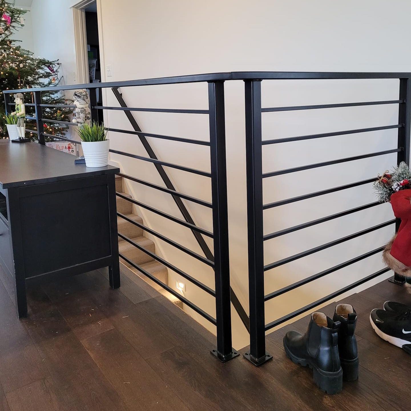 Modern interior stair railing with black steel horizontal rails and matching landing section