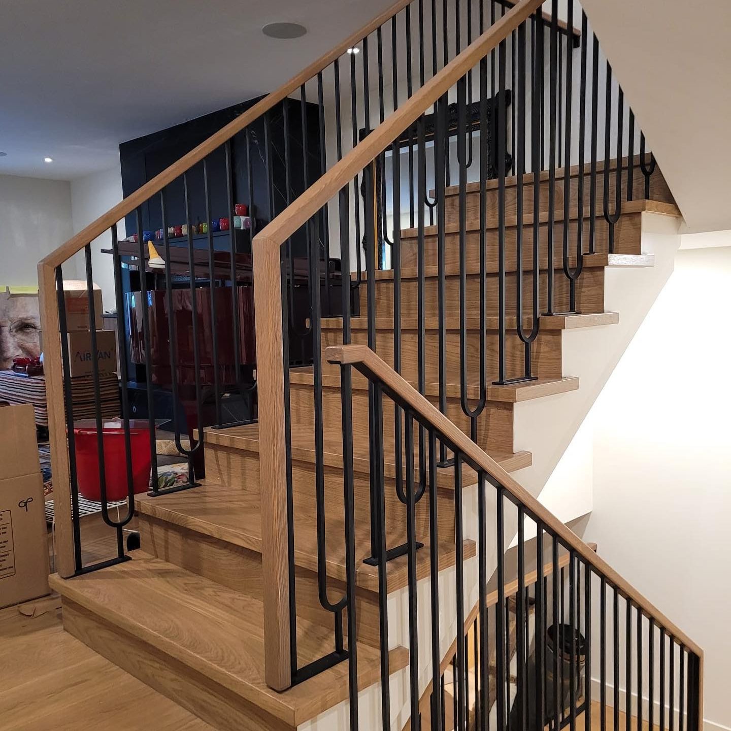 Modern interior stair railing with natural wood handrail and black metal vertical balusters