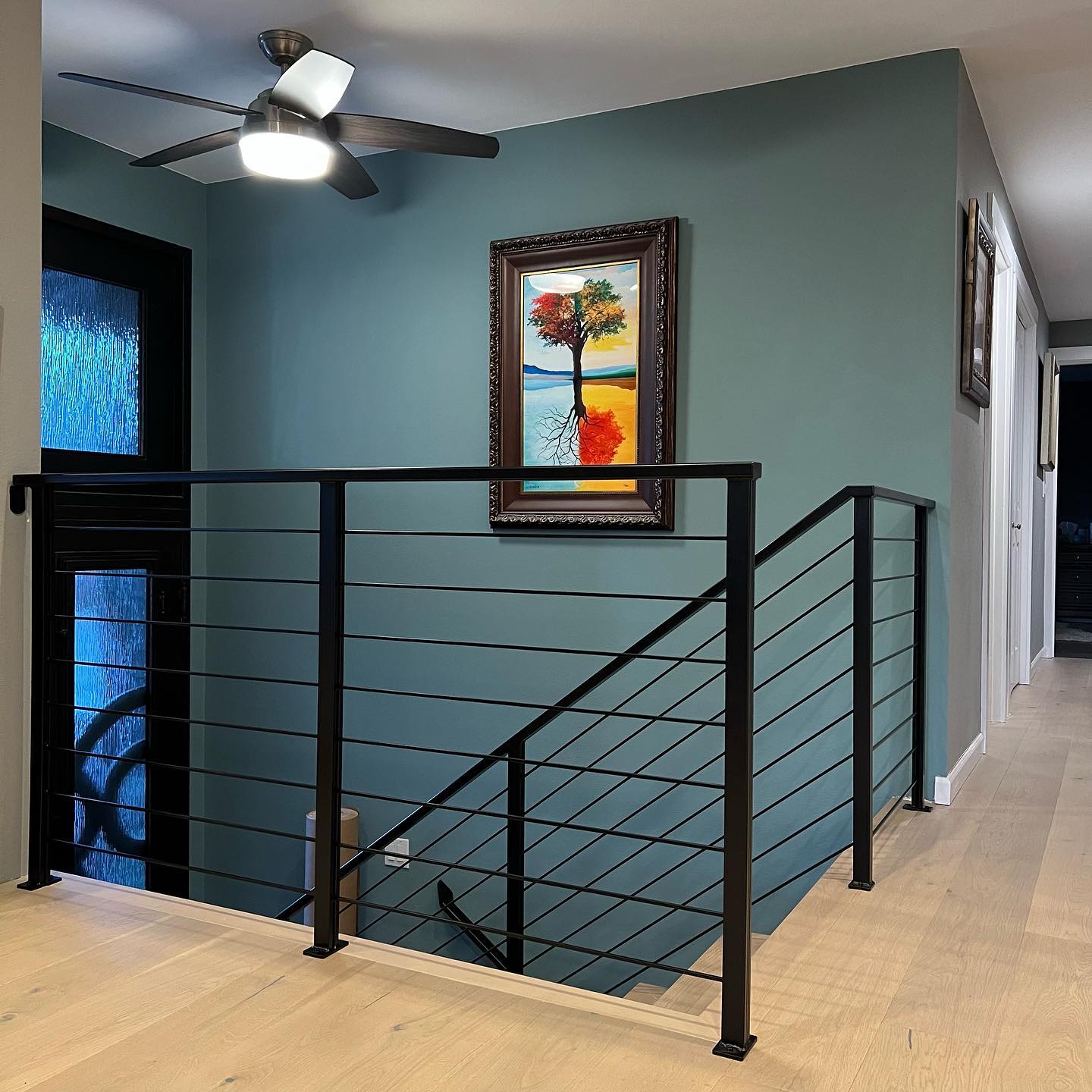 Modern interior landing railing with black metal posts and horizontal rails above a stair opening