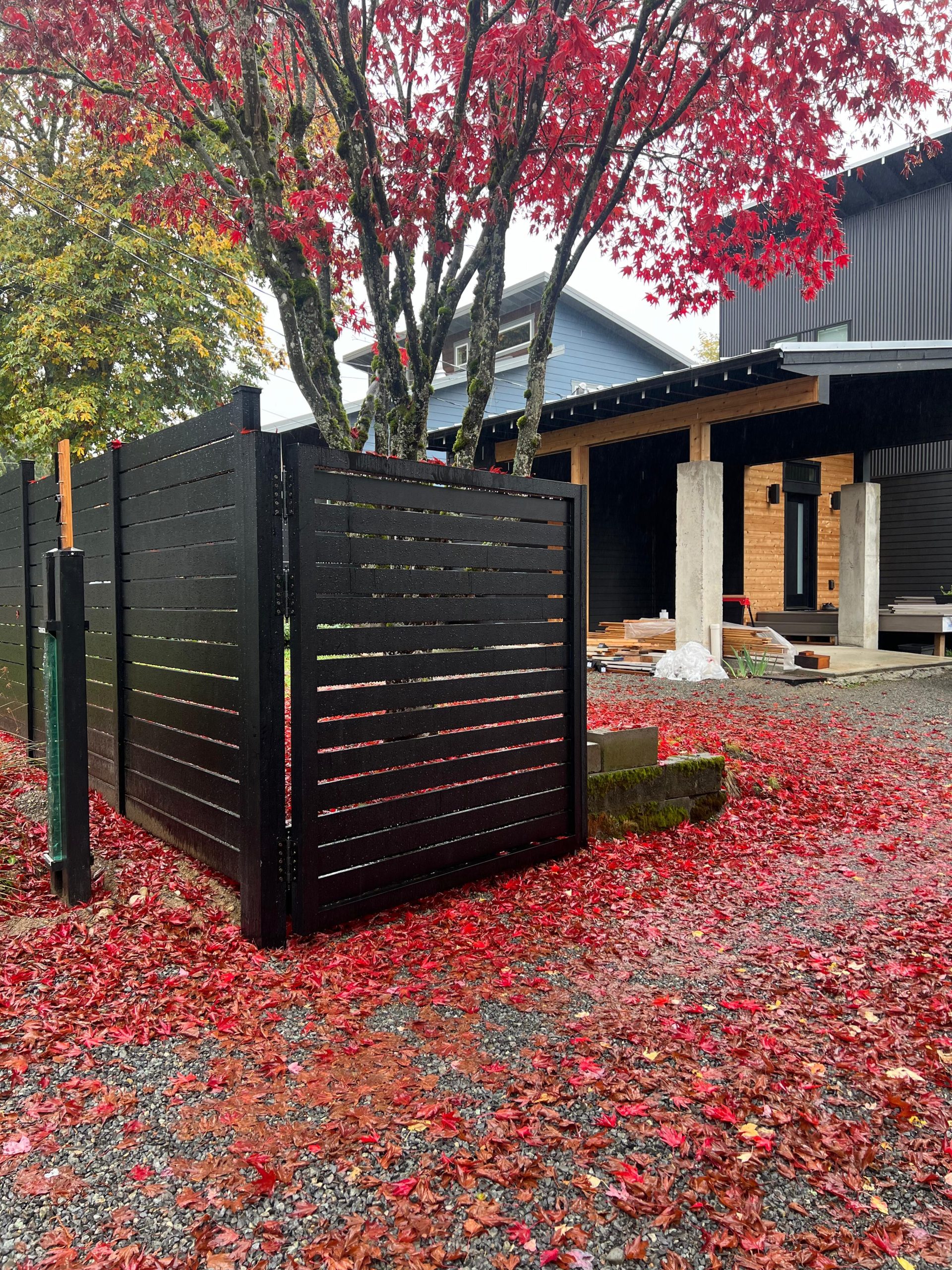 Black aluminum privacy fence with horizontal slats and gap spacing installed along a residential property.